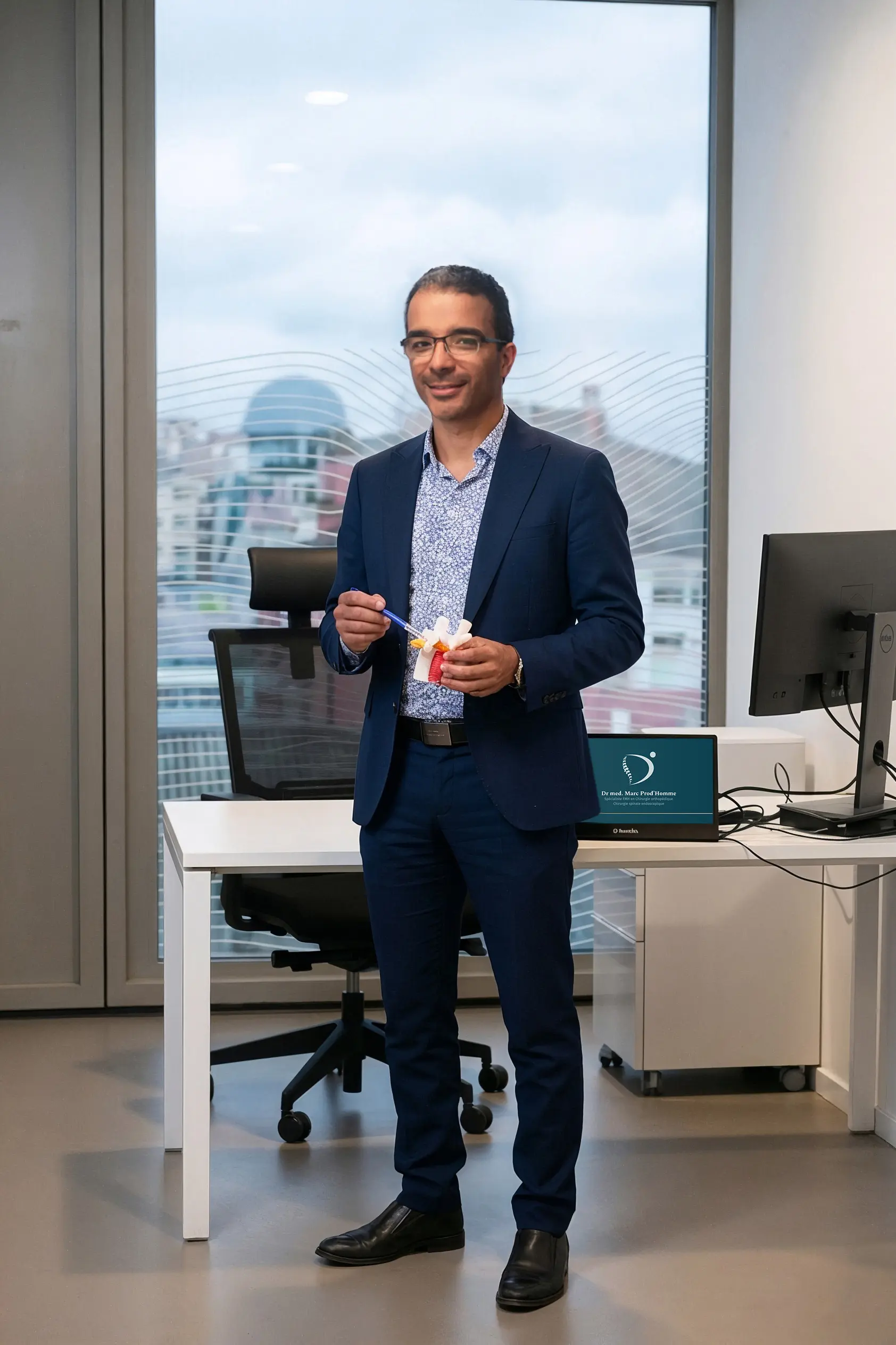 Dr Marc Prod'Homme, spécialiste FMH en chirurgie orthopédique et spinale, avec une maquette de colonne vertébrale.